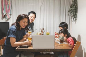 Asian family attending online video call and enjoying dinner together.