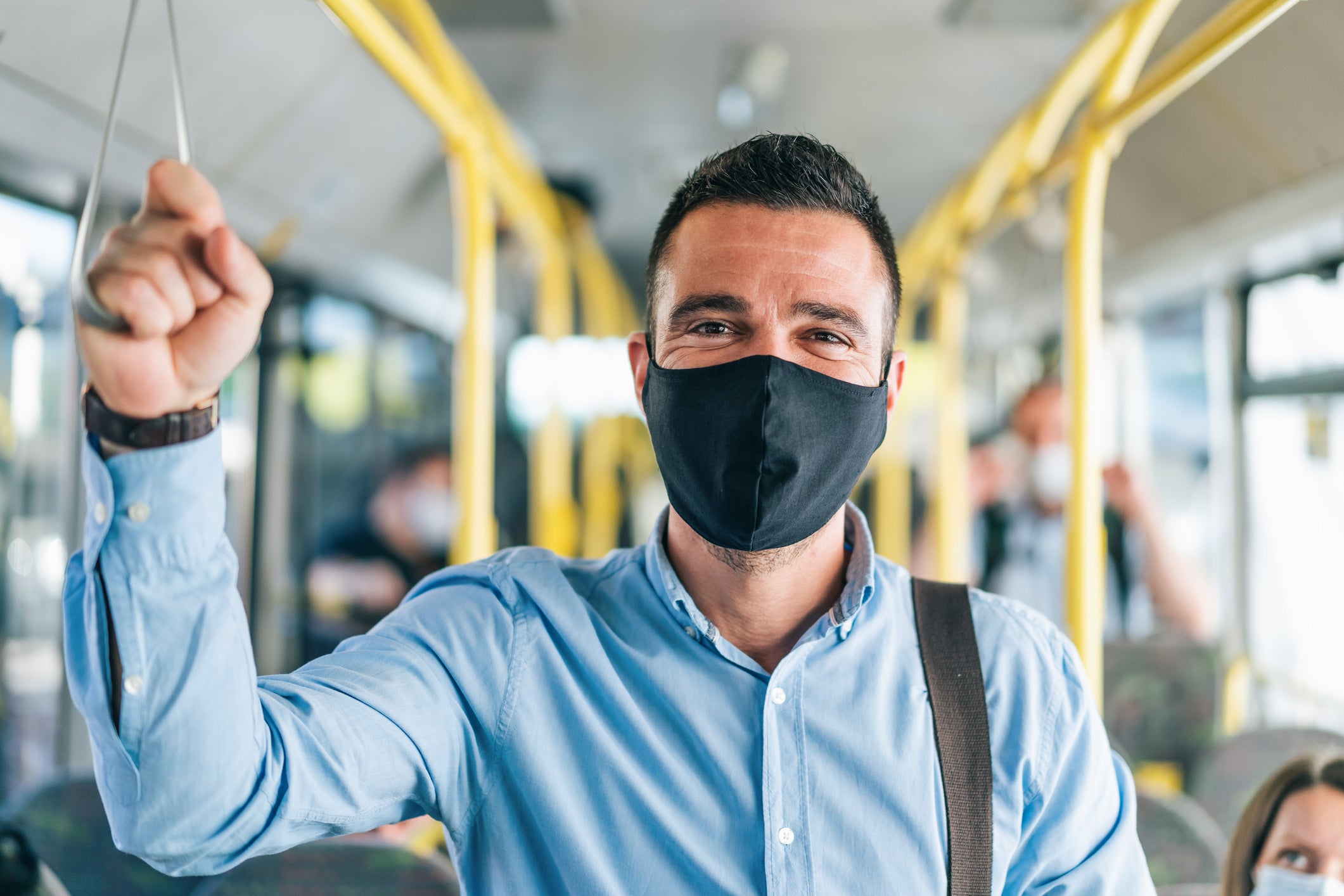 Men traveling in the bus smiling behind a mask.