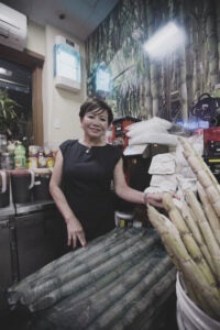 Jennifer stands beside items from the shop. She's wearing a black top with short sleeves.