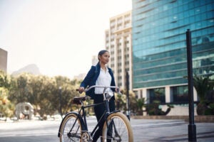 Shot of a young businesswoman traveling with a bicycle through the city
