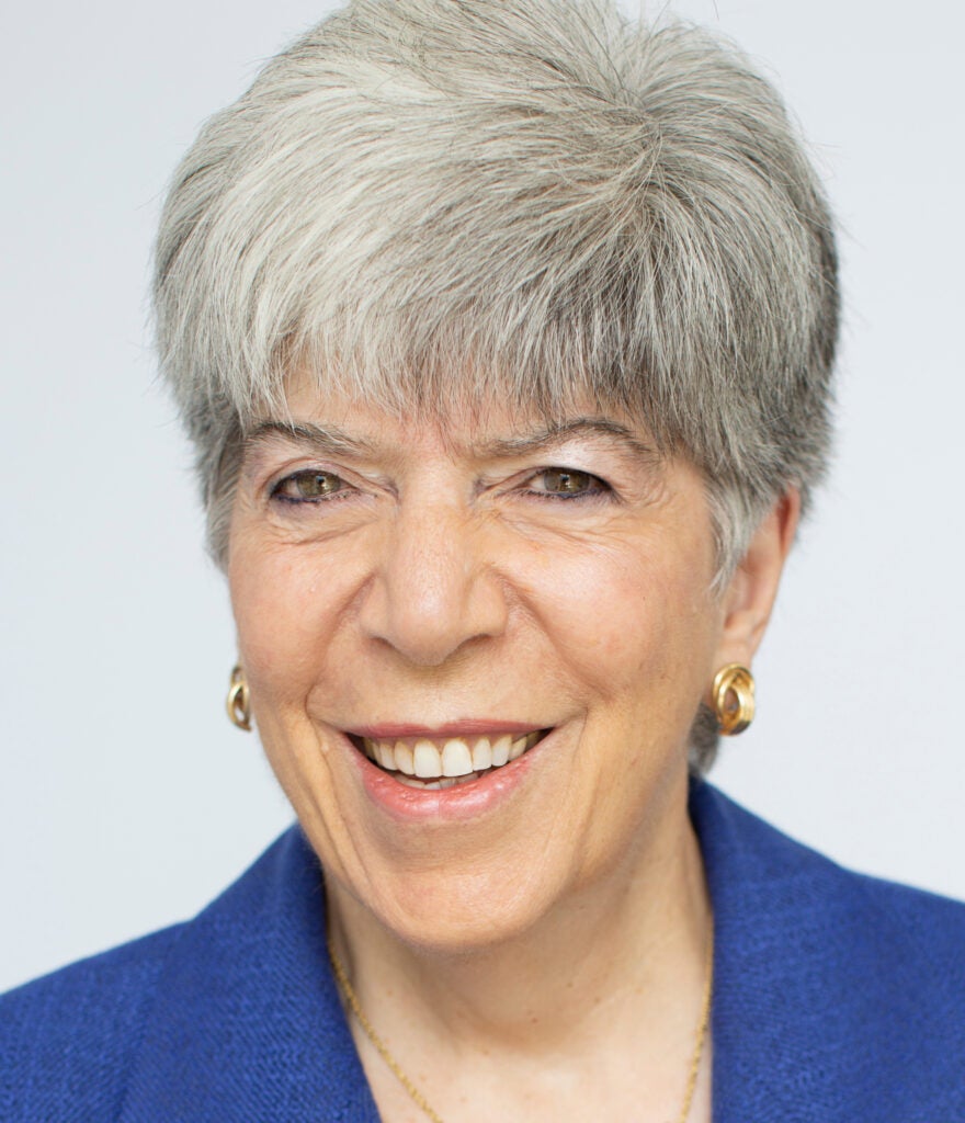 An older woman with short, gray hair wearing a blue blazer  poses for a professional headshot. 