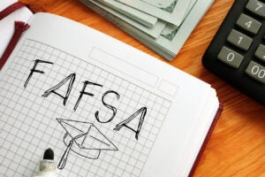 FAFSA written in marker with a graduation cap drawn under it in a graph paper notebook.
