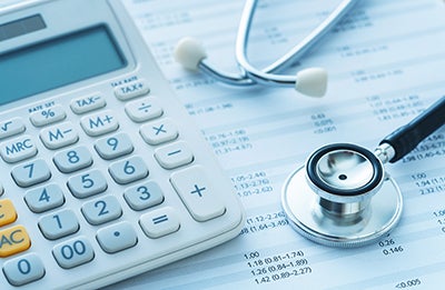 White calculator and stethoscope on top of medical finance insurance papers 