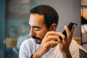 Blind man with beard and mustache using technology to hear what he cannot see.