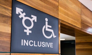 Genderless and handicapped Inclusive public restroom sign with the word inclusive written on it.