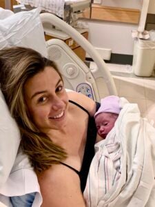 A new mom smiles from a hospital bed while holding her baby