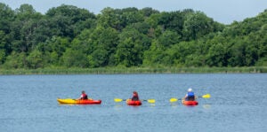 Three family members kayaking on lake together