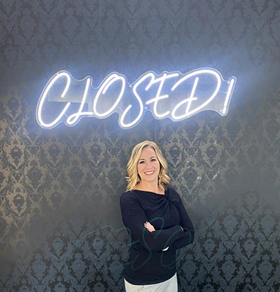 Nicole Choate-DeRosa in front of glowing blue "Closed" sign
