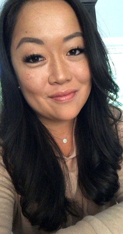 Selfie of woman with long black hair in loose curls wearing long-sleeved beige shirt. 
