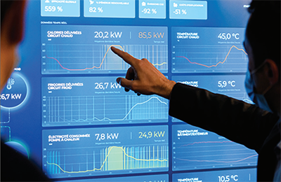 A man points at a blue diagram on a screen that presents data on a geothermal system.