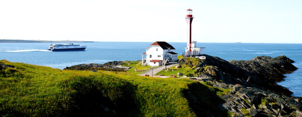 Lighthouse and house on rocky shoreline. 