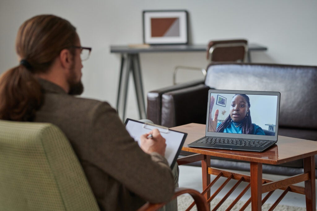 A young woman talking with a psychologist over a video call for a consultation. 