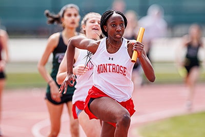 Girl running in a race holding a baton.