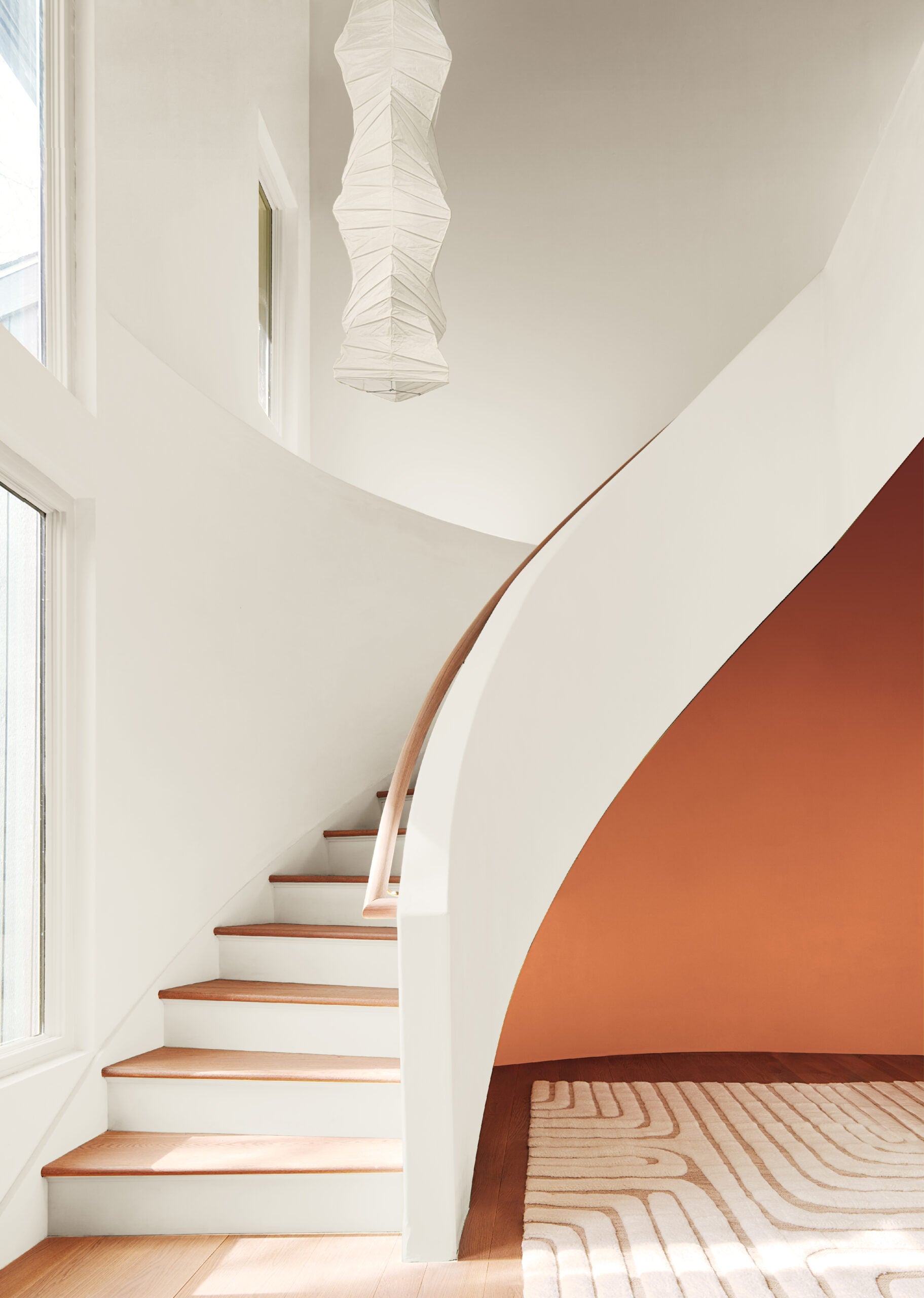 A staircase with a white back wall and a topaz orange accent wall behind it.