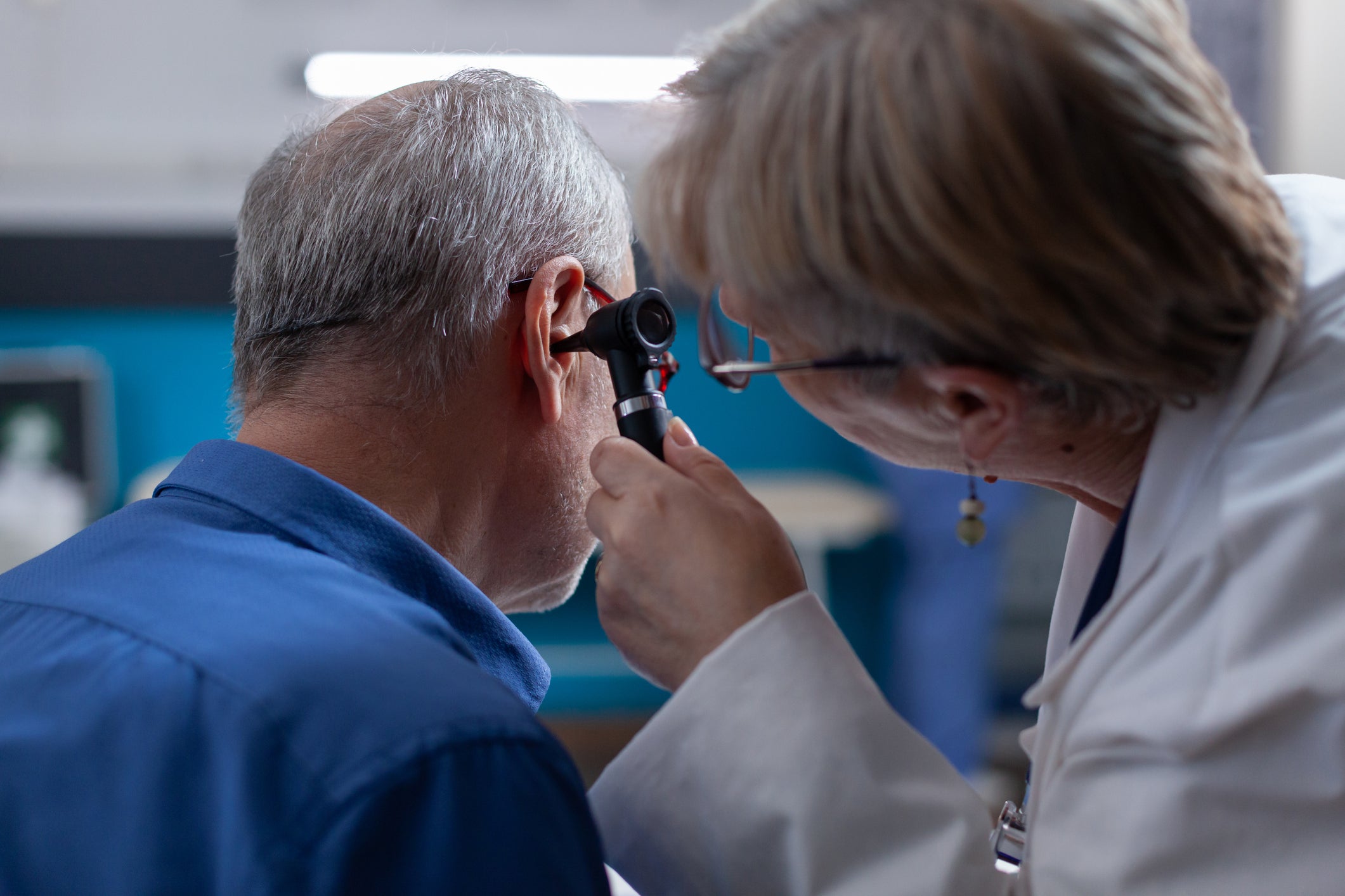 A close up of an older man having his ears checked at the clinic by a female doctor for a routine medical appointment to see if he requires hearing aids