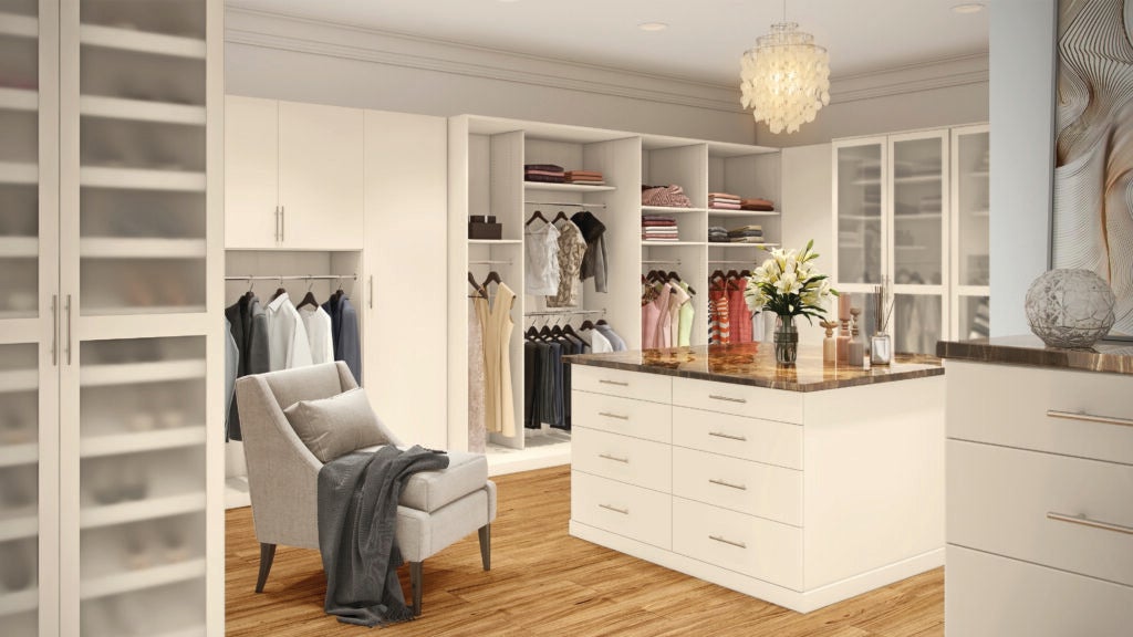 The interior of a large room-sized closet featuring white furniture and wood accents. 