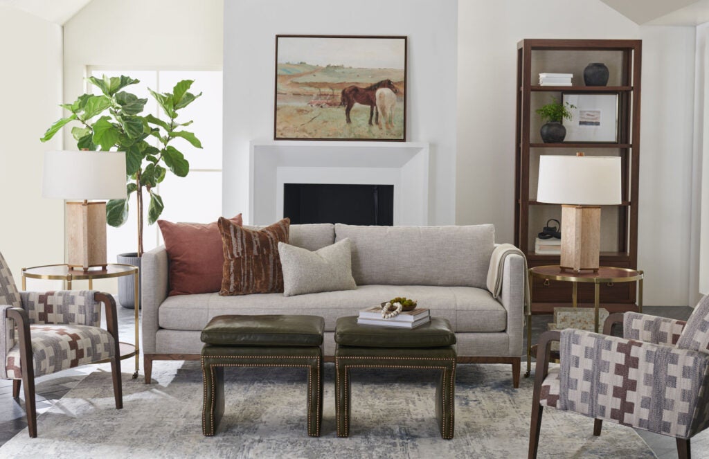 The interior of a living room with white walls, beige and wood furniture, and a horse painting on the wall. 