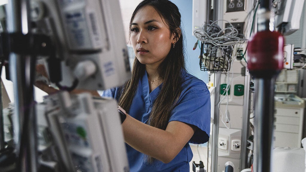 Woman in blue scrubs works off a machine in a hospital