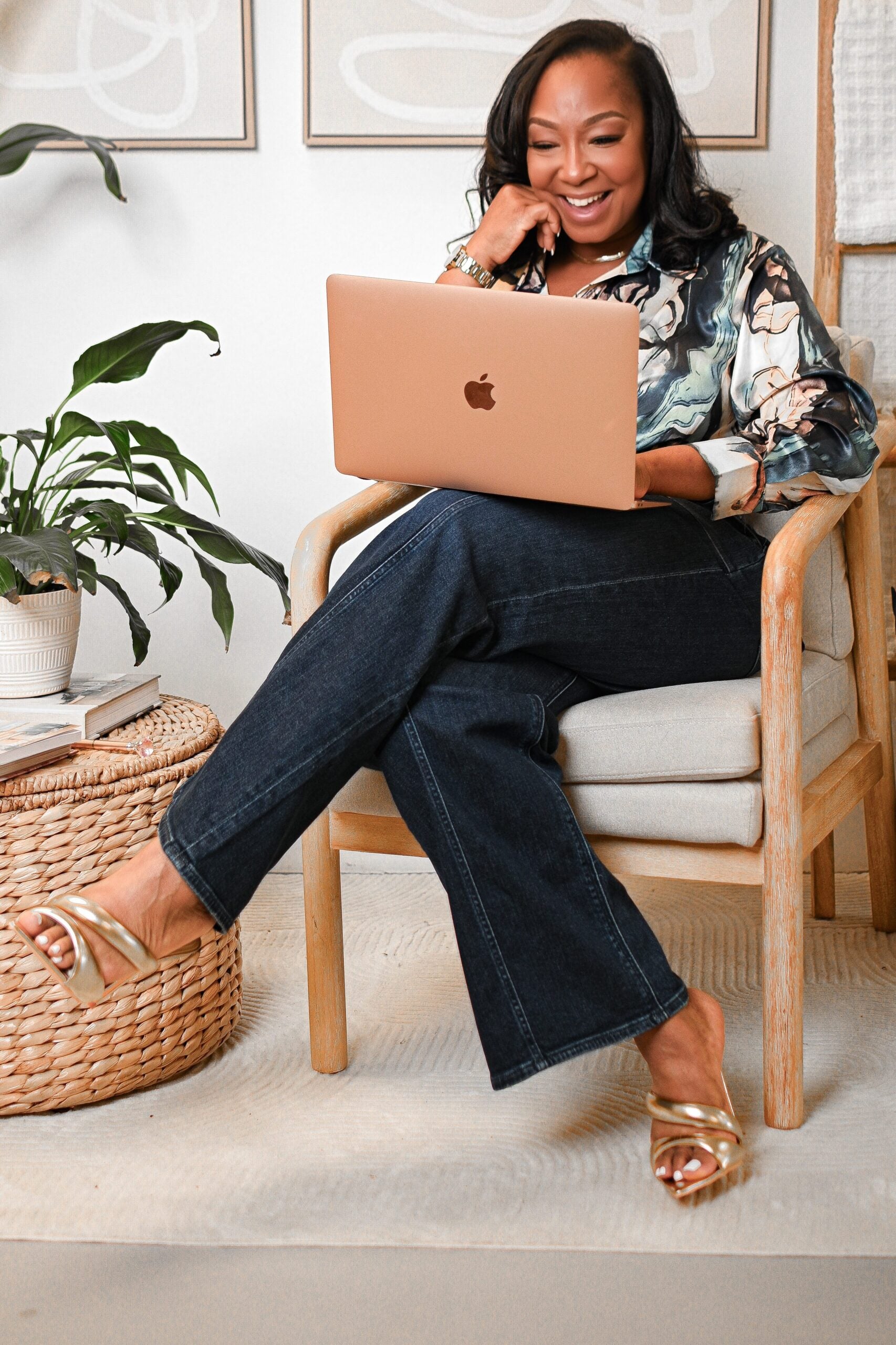 Yori Scott lounges in a chair with her legs crossed. She smiles down at her open laptop.