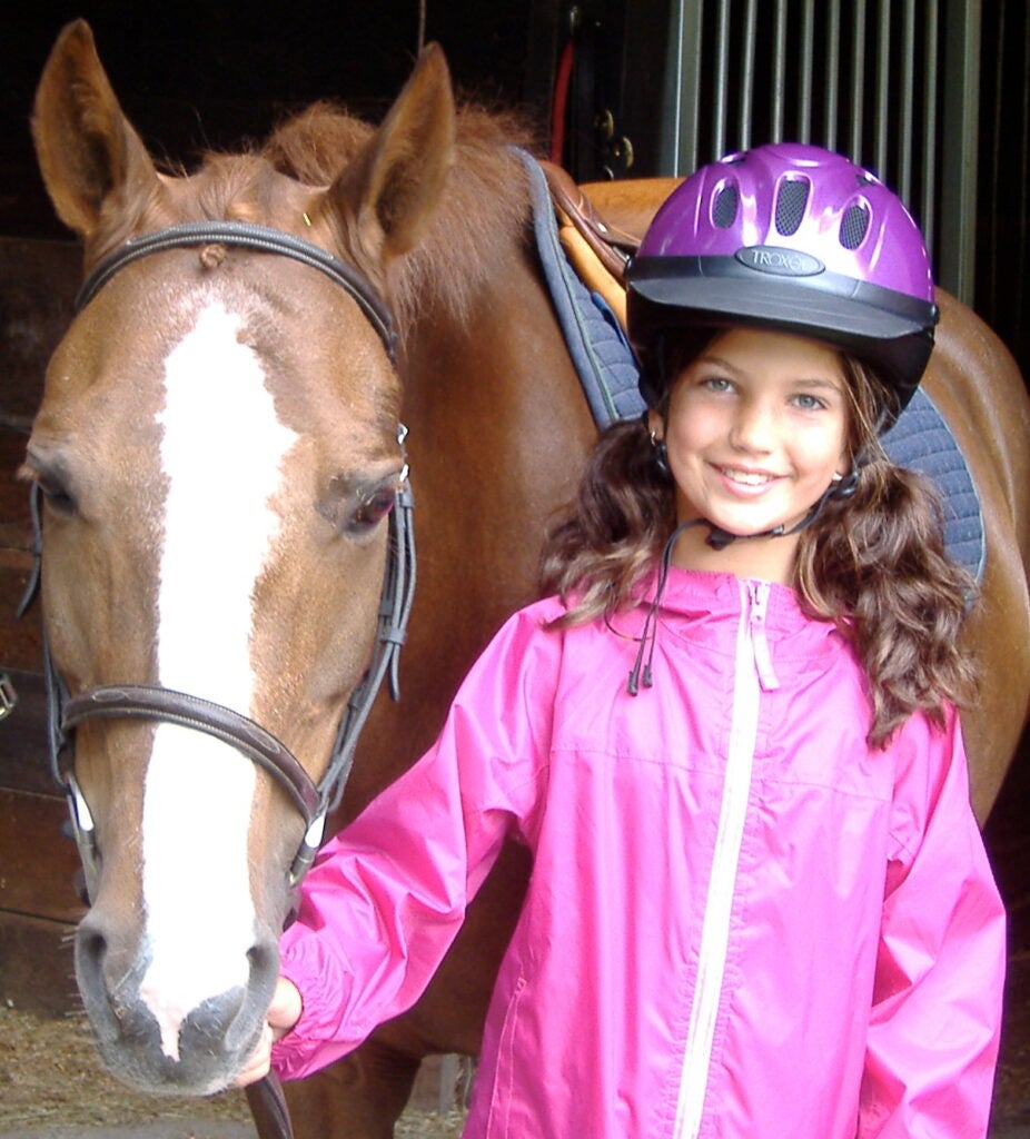 Girl posing alongside her horse