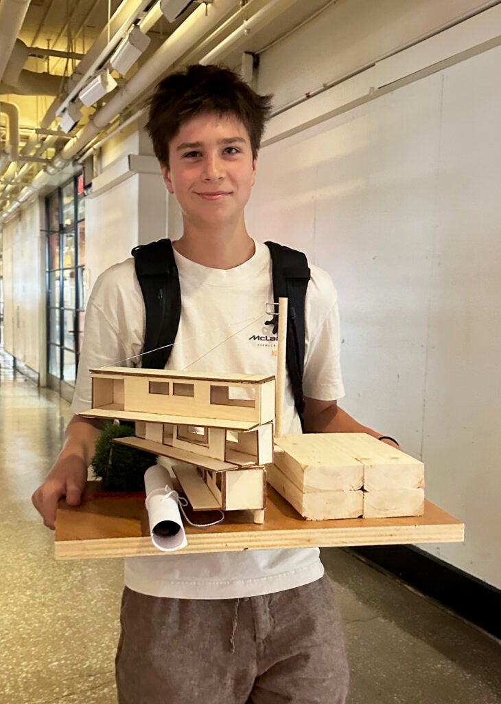 Boy holding a 3-D architecture model of a house 