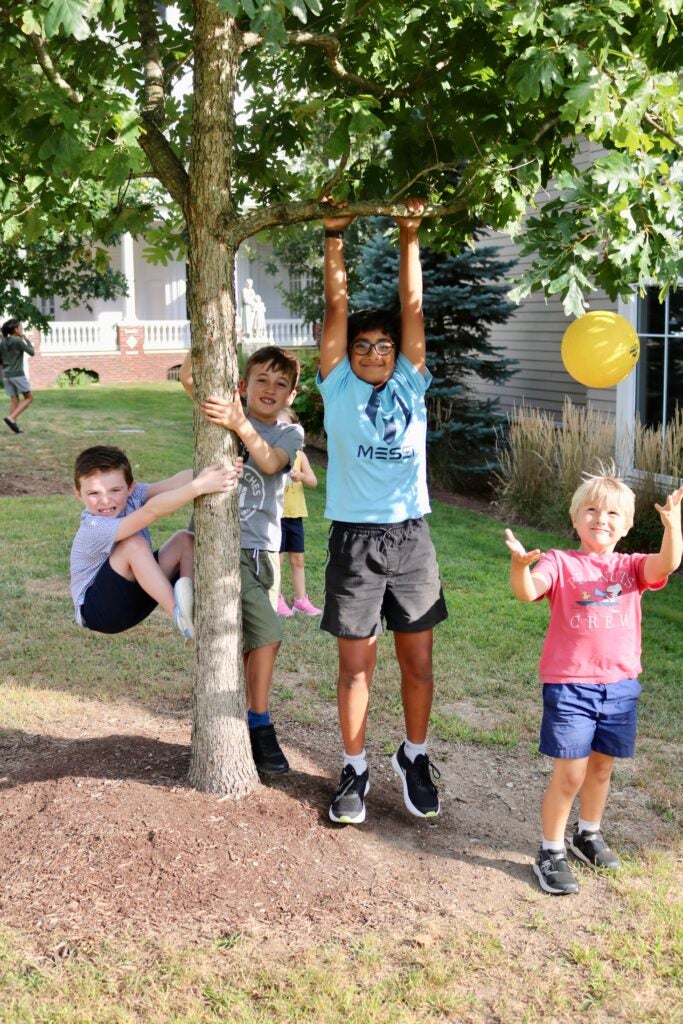 Four kids standing around a tree