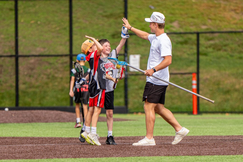 Three campers playing Lacrosse celebrating 