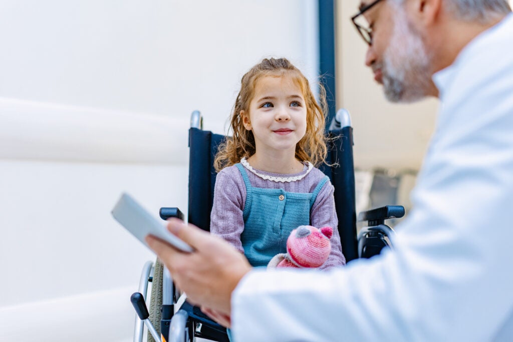 Pediatrician talking to patient in wheelchair