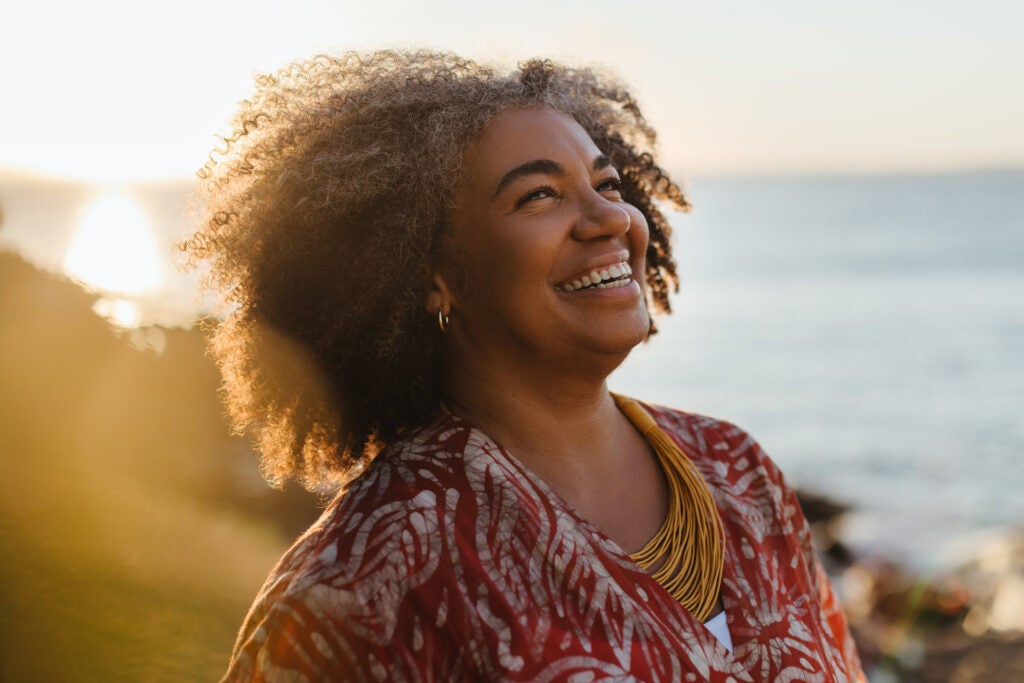 Smiling woman by the sea at sunset