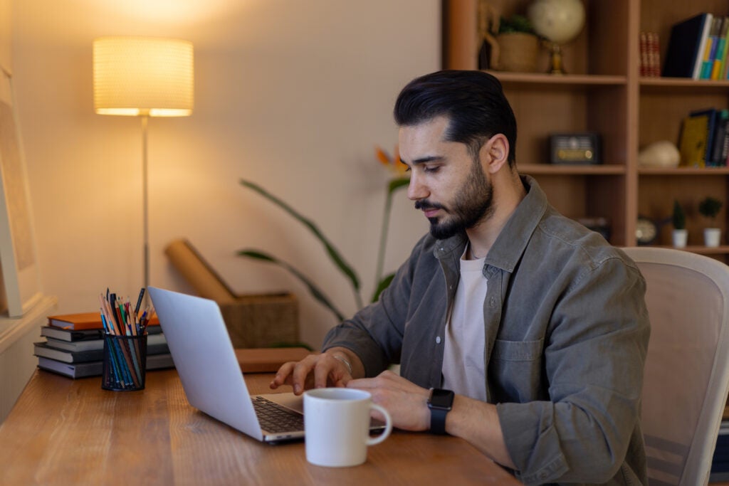 Man sitting at desk and typing on laptop