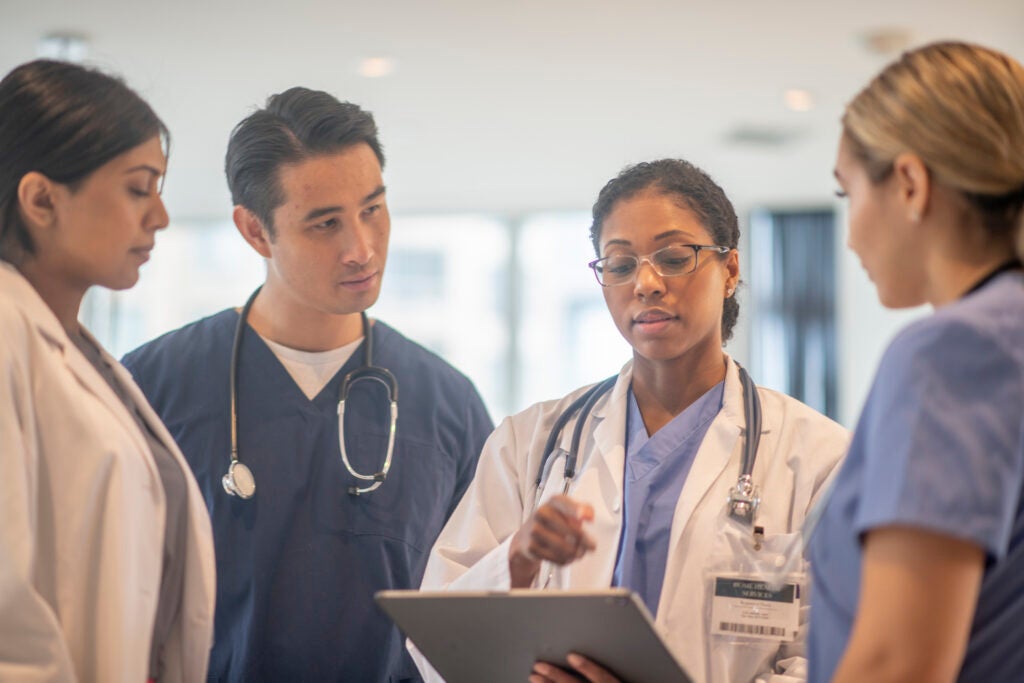 Doctors stand together in the hallway while going over a patient file
