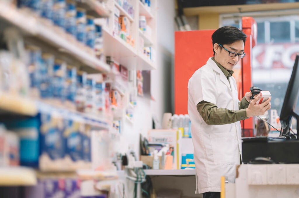 Pharmacy worker scanning prices on his computer
