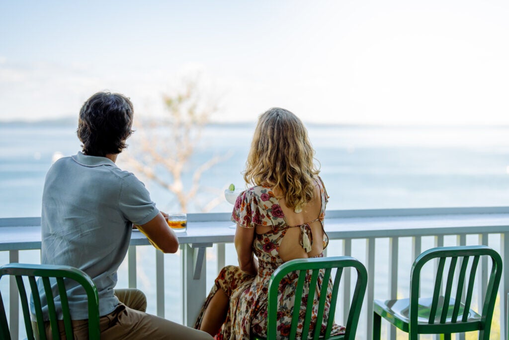 Boy and girl sitting in the hotel balcony overlooking the horizon 